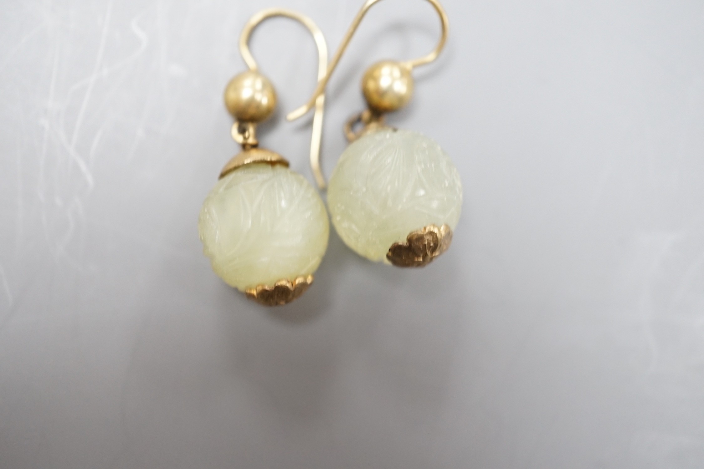 A pair of antique gilt metal and carved hardstone spherical drop earrings, jade diameter 14mm.